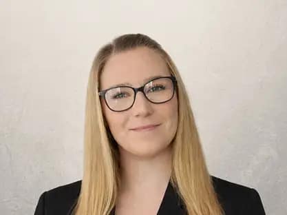 Professional woman with glasses smiling representing operations and marketing role in property investment business support team