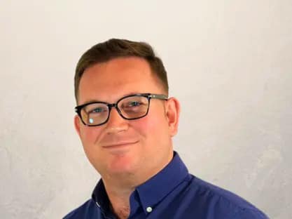 Professional man wearing glasses smiling representing property investment director offering buy to let advice and investor support