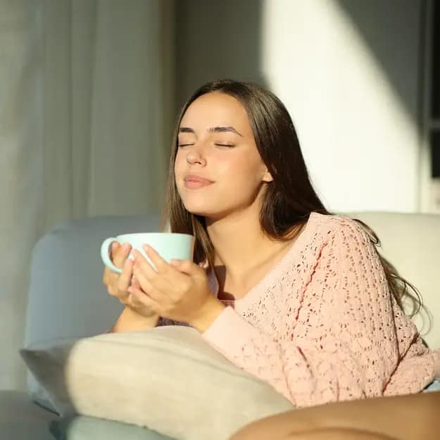 Woman relaxing with cup of tea at home representing comfort and stability in HMO social housing investment living environments